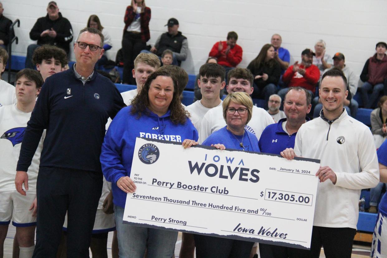 Members of the Perry Booster Club accept a check from the Iowa Wolves during a basketball doubleheader against Greene County on Tuesday, Feb. 6, 2024, at Perry High School.