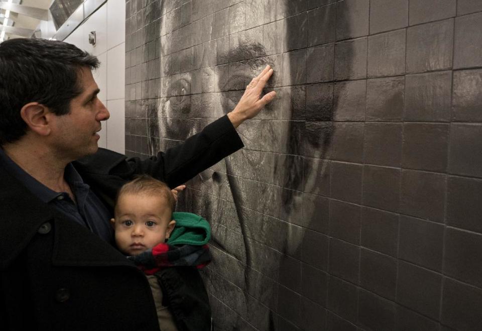 A portrait by artist Chuck Close that graces the wall of the newly opened 86th Street subway station is touched by a passerby as the Second Ave. subway opened to the public Sunday, Jan. 1, 2017, in New York. The opening of three stations on the newly opened Second Ave. subway marks a decades long plan to bring rail transportation to Manhattan's Upper East Side. (AP Photo/Craig Ruttle)