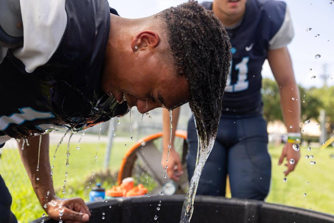 Patrick Lawrence, linebacker, dips his head into the ice bucket to cool off during the Palmetto Panthers football practice on Monday, Aug. 7, 2023 in Pinecrest, Fla.