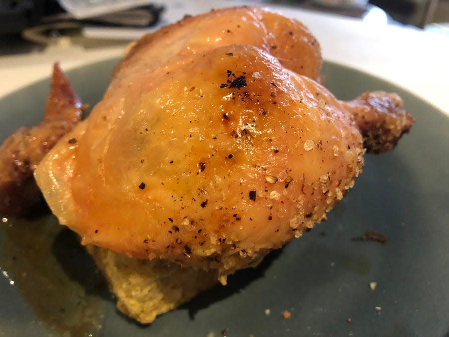 Keller's roast chicken on a black plate.