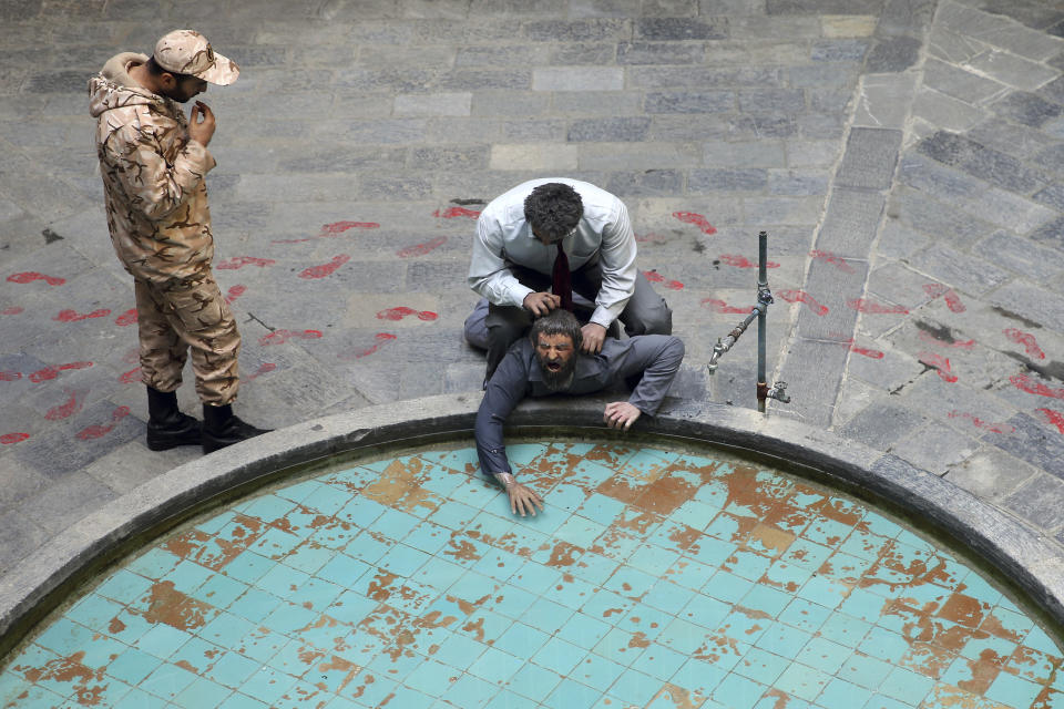 In this Monday, Jan. 7, 2019 photo, a Iranian Revolutionary Guard soldier looks at an exhibition at a former prison run by the pre-revolution intelligence service, SAVAK, now a museum, where a wax mannequin of a snarling interrogator is depicted forcing a prisoner’s head under water, in downtown Tehran, Iran. As Iran marks the 40th anniversary of its Islamic Revolution and the overthrow of the shah, those who suffered torture at the hands of the police and dreaded SAVAK still bear the scars. U.N. investigators and rights group say that even today, Iran tortures and arbitrarily detains prisoners. (AP Photo/Ebrahim Noroozi)
