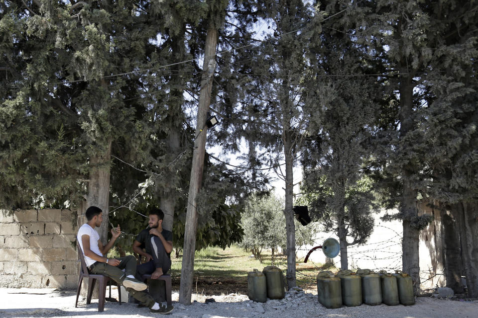 In this Sunday, July 28, 2019 photo, Syrian men wait for customers next to plastic jerrycans of gasoline, in Aleppo, Syria. Syrians say it’s even harder now to make ends meet than it was during the height of their country’s civil war because of intensified U.S and European sanctions. Prices have leaped because of restrictions on oil imports, the value of the currency has plunged in recent months. Most of the country is now below the poverty line, earning less than $100 a month. (AP Photo/Hassan Ammar)