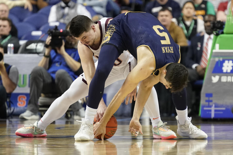 Notre Dame guard Cormac Ryan (5) and Virginia Tech guard Hunter Cattoor (0) vie for possession of the ball during the first half of an NCAA college basketball game at the Atlantic Coast Conference men's tournament in Greensboro, N.C., Tuesday, March 7, 2023. (AP Photo/Chuck Burton)