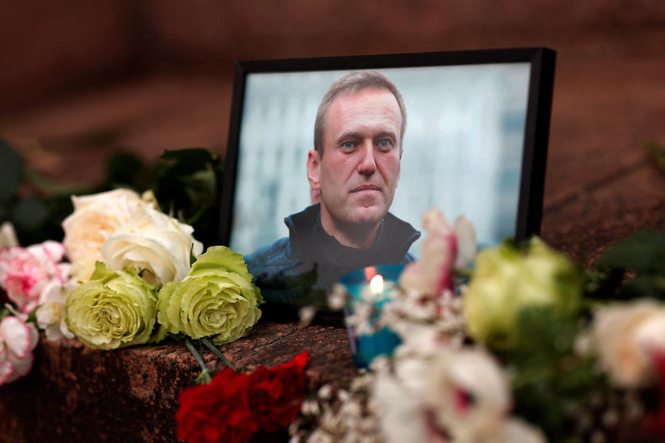 Flores y una vela se colocan junto a un retrato del líder de la oposición rusa Alexei Navalny tras su muerte, mientras la gente se reúne cerca de la embajada rusa, en París, Francia, 16 de febrero de 2024. (REUTERS/Gonzalo Fuentes)