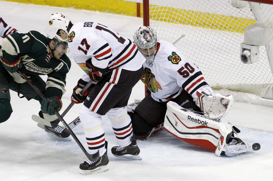 Chicago Blackhawks goalie Corey Crawford (50) deflects a shot in front of Blackhawks defenseman Sheldon Brookbank (17) and Minnesota Wild left wing Zach Parise (11) during the first period of Game 6 of an NHL hockey second-round playoff series in St. Paul, Minn., Tuesday, May 13, 2014. (AP Photo/Ann Heisenfelt)