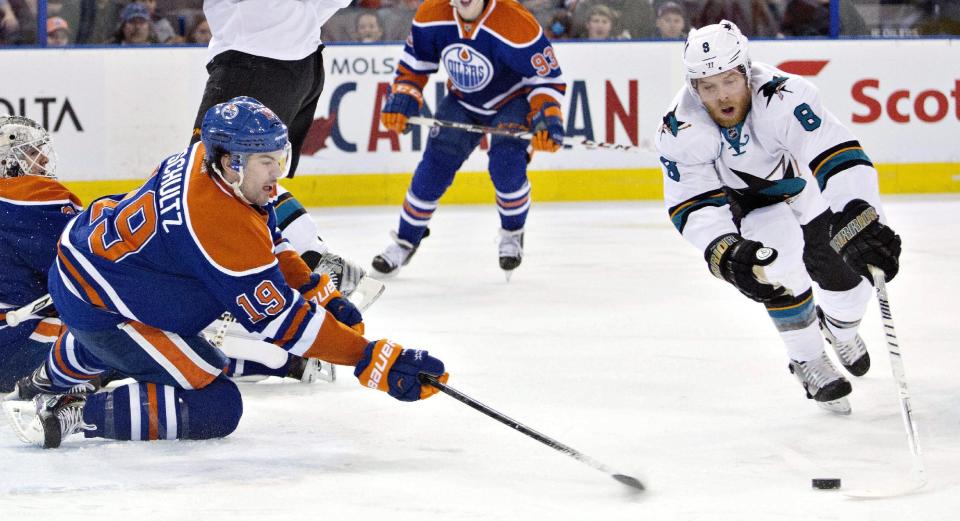 San Jose Sharks Joe Pavelski (8) and Edmonton Oilers Justin Schultz (19) reach for the loose puck during the first period of an NHL hockey game in Edmonton, Alberta, on Wednesday, Jan. 29, 2014. (AP Photo/The Canadian Press, Jason Franson)