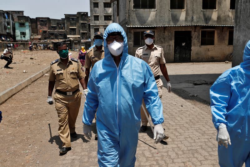 Health workers wearing hazmat suits and masks are accompanied by police officers as they conduct an inspection in a residential area, during a nationwide lockdown in India to slow the spread of COVID-19, in Dharavi, one of Asia's largest slums, during the coronavirus disease outbreak, in Mumbai