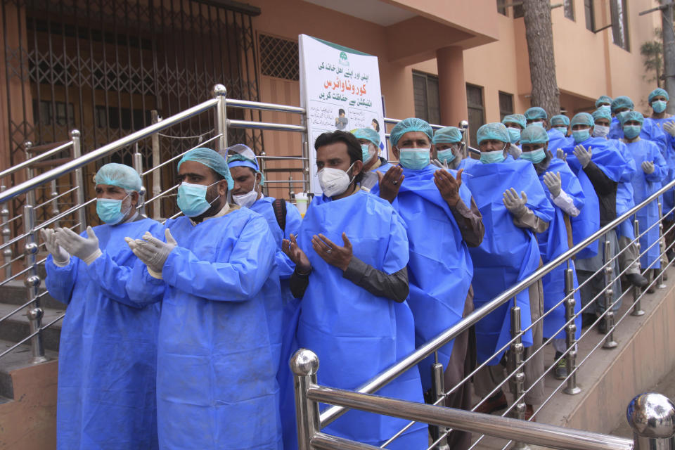 Personal médico de un hospital se une en una oración antes de iniciar su turno laboral, en el exterior de un centro hospitalario que recibe pacientes contagiados de coronavirus, en Quetta, Pakistán, el jueves 26 de marzo de 2020. (AP Foto/Arshad Butt)