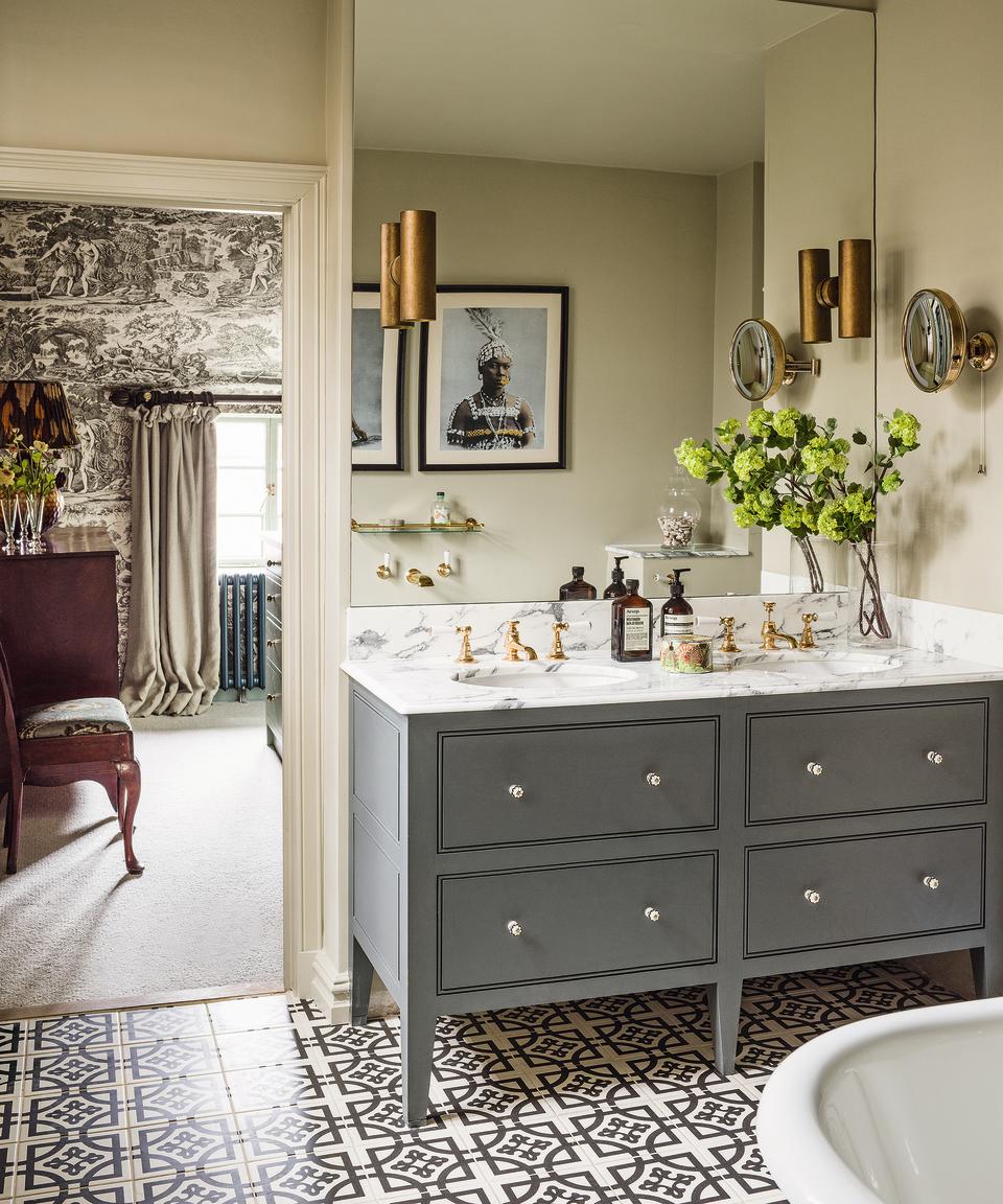 monochrome pattern on the wallpaper in the bedroom is complimented by a similarly colored pattern on the bathroom floor, and the rich copper hue on the lampshade is echoed by the bathroom lighting