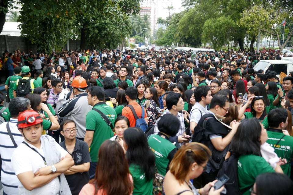 Office employees, some wearing hard hats, gather in the open as they file out of their building following a magnitude 5.5 that rocked some areas of the country's north, including in the capital, that also briefly disrupted train services Friday, Sept. 13, 2019 in Manila, Philippines. The Philippine Institute of Seismology and Volcanology says Friday's quake was centered about 40 kilometers northeast of the coastal town of Burdeos in northeastern Quezon province and was caused by movement in a local fault at a shallow depth of 10 kilometers (6 miles). There were no immediate reports of injuries or damages. (AP Photo/Bullit Marquez)