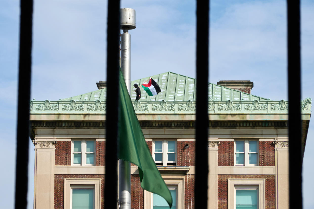A masked protester waves the Palestinian flag from the roof as the occupation of Hamilton Hall continues on the campus of Columbia University in New York on Tuesday afternoon, April 30, 2024. (Bing Guan/The New York Times)