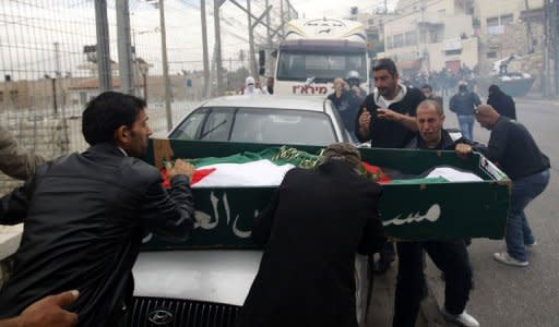 Palestinian mourners steady the coffin of a teenager who died after being shot during his funeral in the East Jerusalem neighbourhood of Ras al-Amud