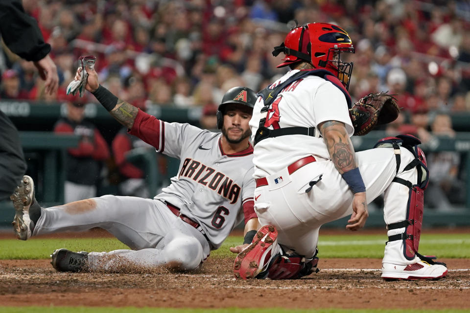 Arizona Diamondbacks' David Peralta (6) scores past St. Louis Cardinals catcher Yadier Molina during the sixth inning of a baseball game Friday, April 29, 2022, in St. Louis. (AP Photo/Jeff Roberson)