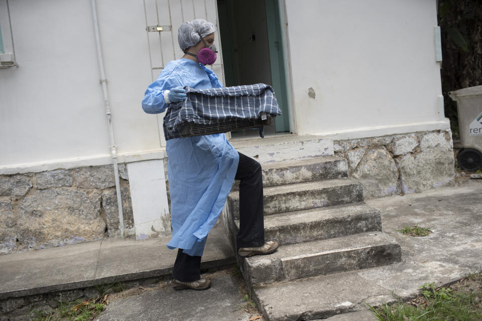 A researcher for Brazil's state-run Fiocruz Institute, wearing protective gear, transports captured monkeys to a holding area, at Pedra Branca state park, near Rio de Janeiro, Tuesday, Oct. 29, 2020. Researchers at the institute collect and study viruses present in wild animals — including bats, which many scientists believe were linked to the outbreak of COVID-19. (AP Photo/Silvia Izquierdo)