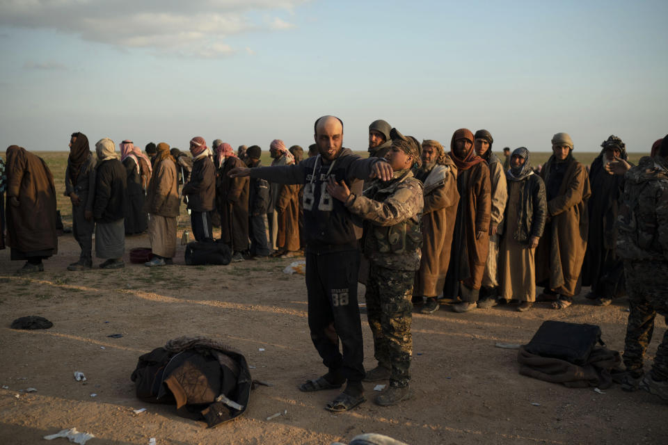 FILE - In this Feb. 22, 2019 file photo, a man is frisked by a U.S.-backed Syrian Democratic Forces (SDF) fighter after being evacuated out of the last territory held by Islamic State militants, near Baghouz, eastern Syria. The SDF fighters who drove the Islamic State from its last strongholds called Monday, March 25, 2019, for an international tribunal to prosecute hundreds of foreigners rounded up in the nearly five-year campaign against the extremist group. (AP Photo/Felipe Dana, File)