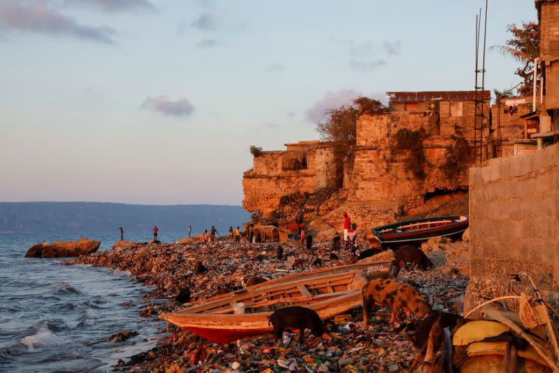 People are seen on the trash-strewn shoreline of Nan Palan in Port-de-Paix