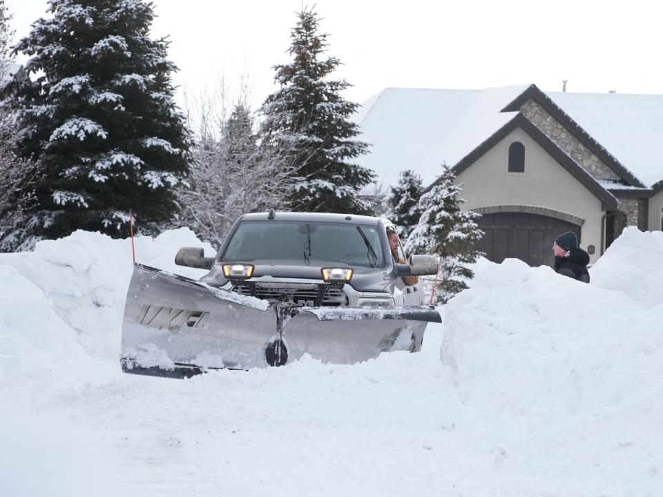 A snowplow driver talks to a homeowner while removing feet of snow from a residential street in Draper, Utah, on February 23, 2023.