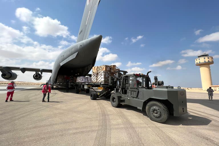 Voluntarios de las organizaciones humanitarias de Qatar y de la Media Luna Roja de Egipto descargan ayuda destinada a los palestinos de la Franja de Gaza en el aeropuerto egipcio de El-Arish, en el norte de la península del Sinaí, el 22 de octubre de 2023, en medio de las batallas en curso entre Israel y el grupo palestino Hamás.