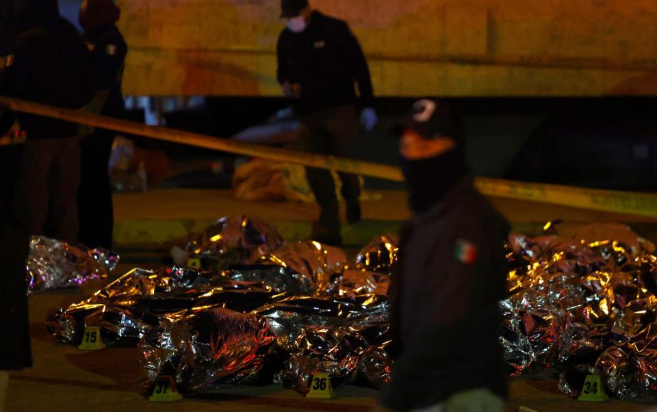 Mexican authorities stand near the bodies of the deceased, mostly from Venezuela, who died in a fire inside the National Migration Institute (INM) building - Reuters