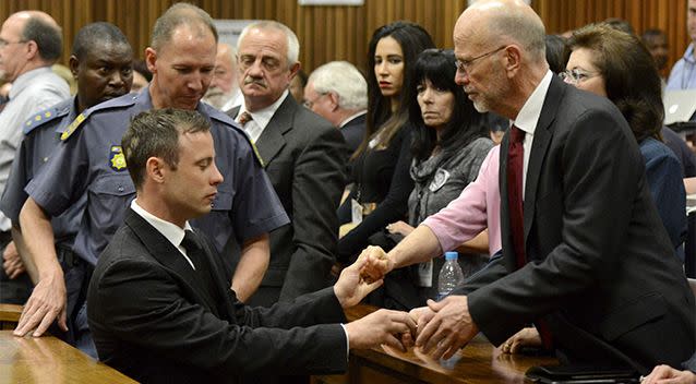 Oscar Pistorius, left front, greets his uncle Arnold Pistorius, right, and other family members as he is led out of court. Photo: AP