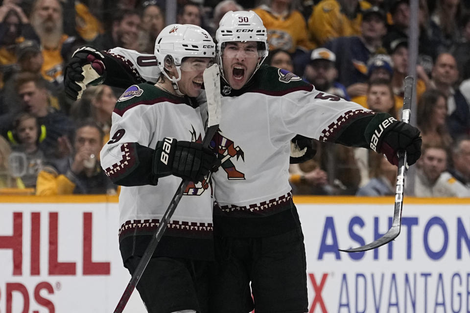 Arizona Coyotes defenseman Sean Durzi (50) and right wing Clayton Keller, left, celebrate a goal against the Nashville Predators during the third period of an NHL hockey game Saturday, Nov. 11, 2023, in Nashville, Tenn. The Coyotes won 7-5. (AP Photo/George Walker IV)