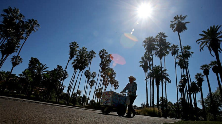 An ice cream vendor pushes a cart on the sidewalk that rings Echo Park Lake in Echo Park. (Credit: Los Angeles Times)