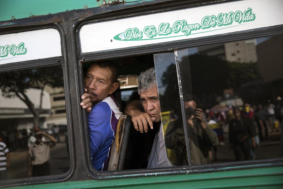 In this Nov. 16, 2019 photo, commuters look at a small group anti-government demonstrators from a passing bus in Maracaibo, Venezuela. In Maracaibo, located in Venezuela’s western Zulia state along the Colombian border, many residents say they’ve abandoned political marches, lacking faith in leaders or fearing for their personal safety. (AP Photo/Rodrigo Abd)
