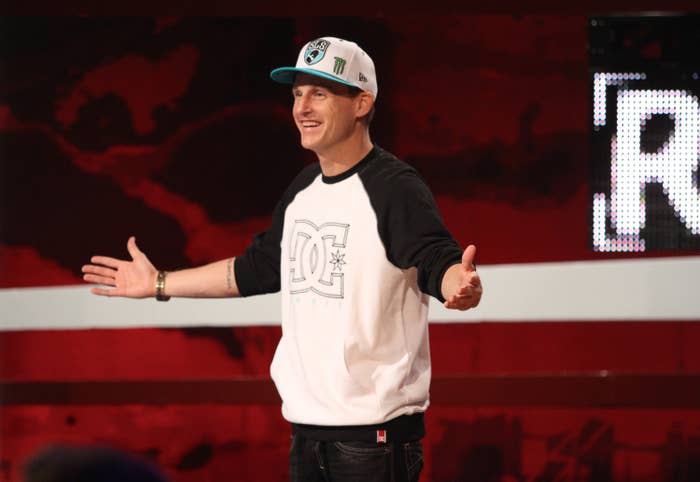 The host of Ridiculousness  smiles as he addresses the audience during an episodeof the show. He's wearing a long-sleeved shirt, baseball cap, and jeans