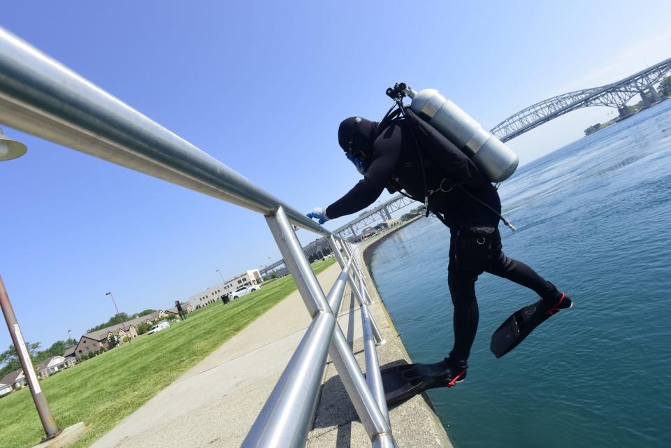 Tim Massey, a Shelby Township resident, puts on scuba-diving gear before jumping in the St. Clair River off the boardwalk at the Thomas Edison Parkway in Port Huron on Wednesday, June 15, 2022.