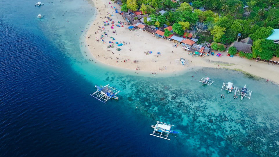 Aerial view of saAerial view of sandy beach in beautiful clear sea water of the Sumilon island beach landing near Oslob, Cebu, Philippines. (Photo: Getty Images)ndy beach with tourists swimming in beautiful clear sea water of the Sumilon island beach landing near Oslob, Cebu, Philippines. - Boost up color Processing.