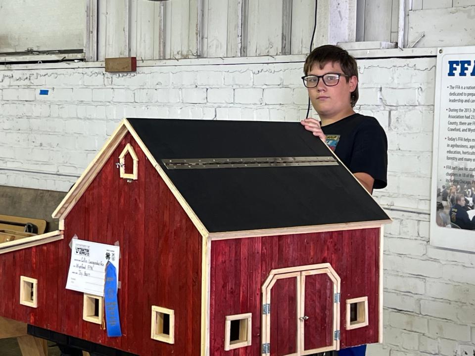 Eleven-year-old Bentley Steffan checks out a wooden barn in the Wynford FFA building on Monday during the Crawford County Fair.