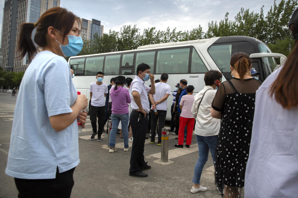 People gather as they wait to be taken by bus to a COVID-19 testing site after they were ordered by the government to be tested after potentially being exposed to the coronavirus outbreak at a wholesale food market in Beijing, Wednesday, June 17, 2020. As the number of cases of COVID-19 in Beijing climbed in recent days following an outbreak linked to a wholesale food market, officials announced they had identified hundreds of thousands of people who needed to be tested for the coronavirus. (AP Photo/Mark Schiefelbein)