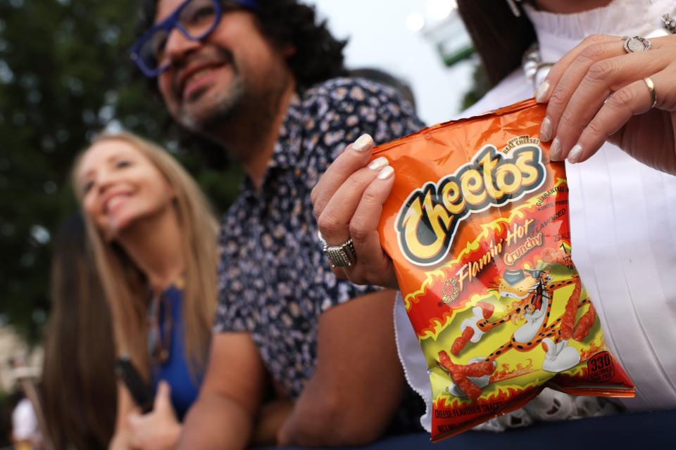 A woman holds bag of Flamin' Hot Cheetos.