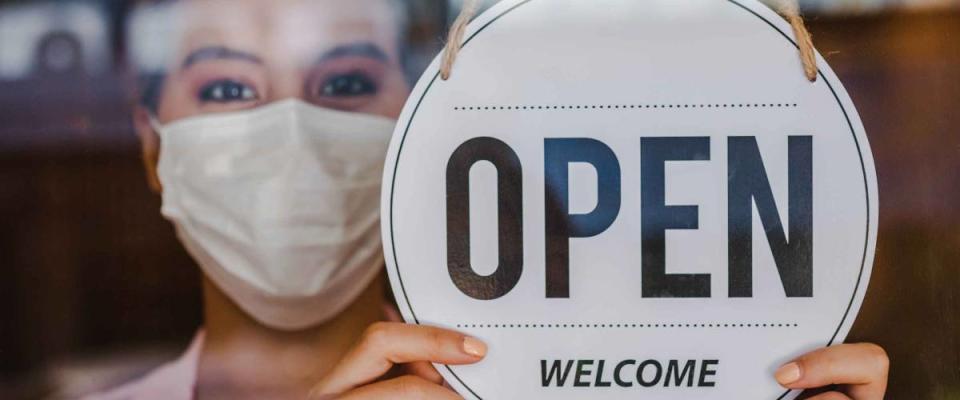 Smiling young asian owner retail,coffee shop woman turning sign board to open wearing face mask,protect to pandemic