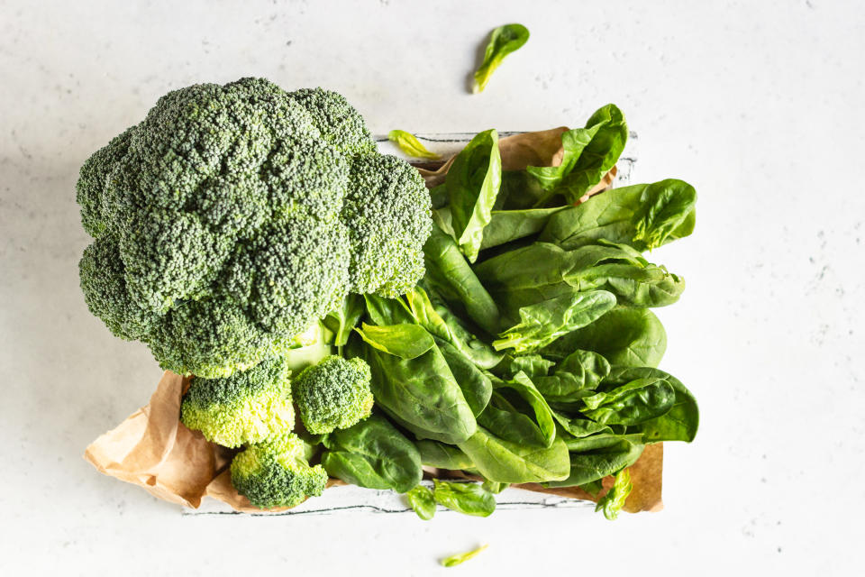 Healthy green vegetables with broccoli and spinach on a wooden tray.