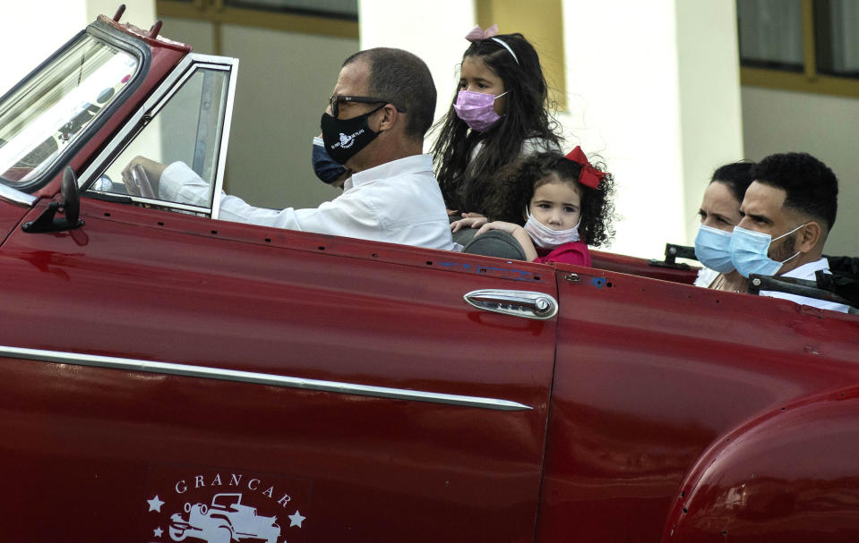 People wearing masks as a precaution against the spread of the new coronavirus, travel in a classic American car in Havana, Cuba, Tuesday, Jan. 12, 2021. (AP Photo / Ramon Espinosa)