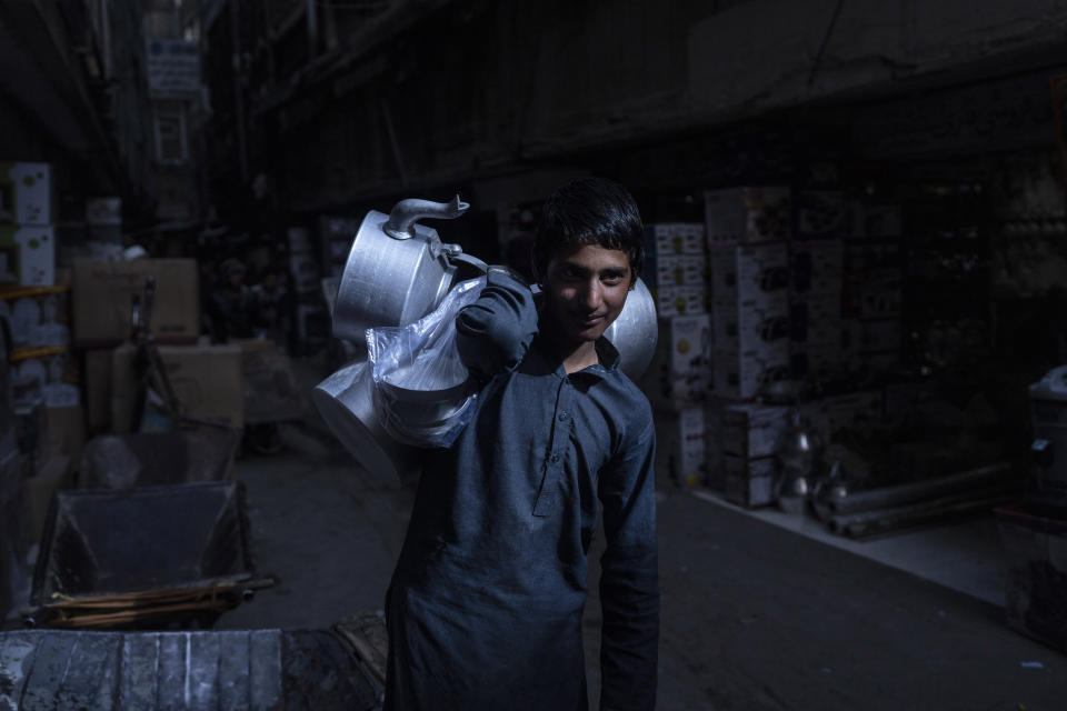 A boy selling teapots walks through a market in Kabul, Afghanistan, Tuesday, Nov. 16, 2021. (AP Photo/Petros Giannakouris)