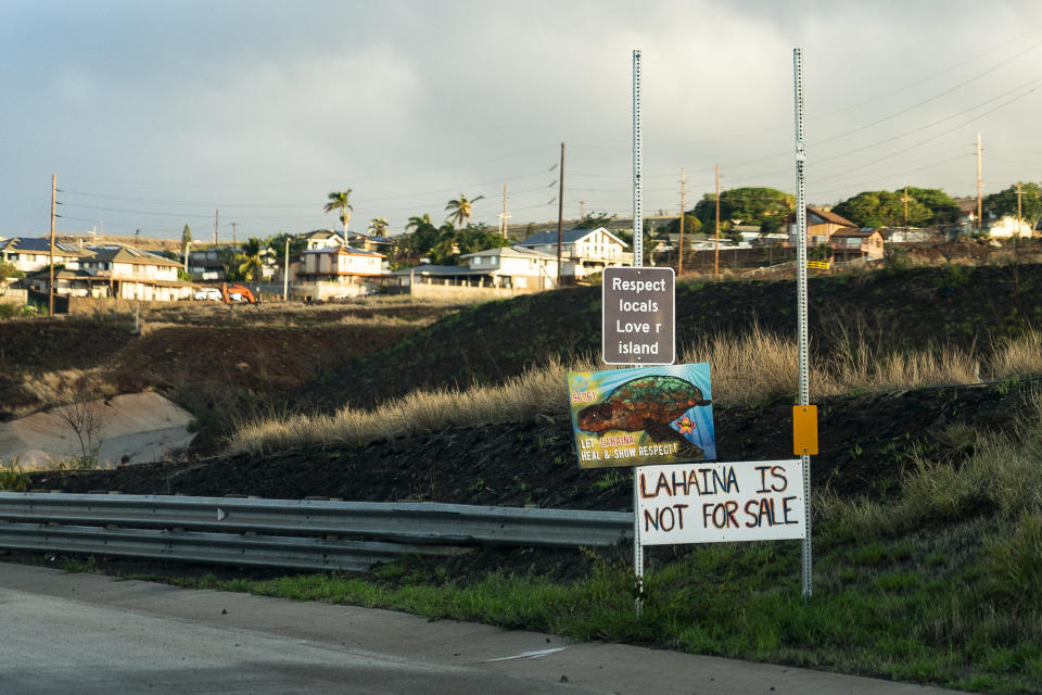 Signs asking people to respect locals and that "Lahaina is not for sale" are seen on the side of the Lahaina Bypass, Wednesday, Dec. 6, 2023, in Lahaina, Hawaii. Residents and survivors still dealing with the aftermath of the August wildfires in Lahaina have mixed feelings as tourists begin to return to the west side of Maui. (AP Photo/Lindsey Wasson)
