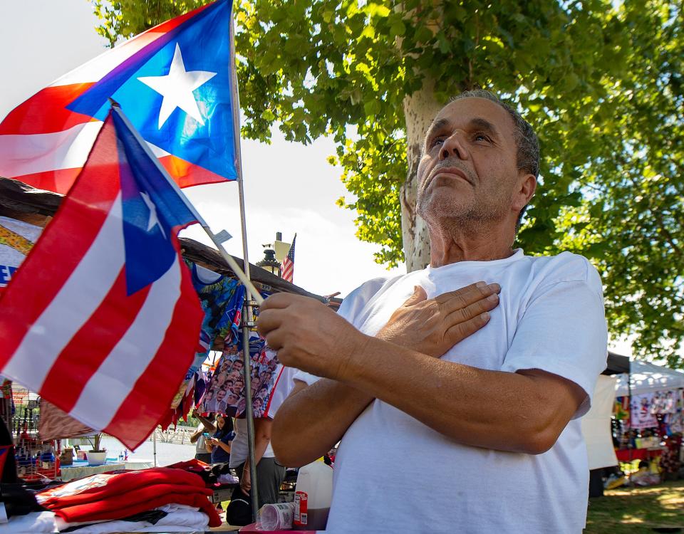 While holding the flag of Puerto Rico, Virgilio Rios, of Philadelphia, stands during the playing of the National Anthem, during opening ceremonies at the 49th annual Puerto Rican Day Festival, held in Bristol Borough on Saturday, July 30, 2022.
