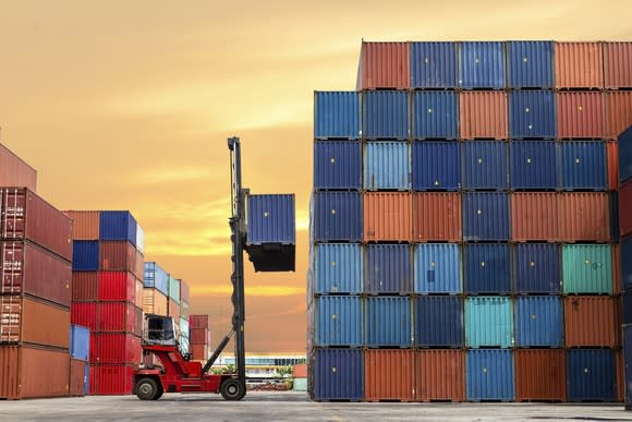 A shipping yard, where shipping containers are being stacked on top of one another.