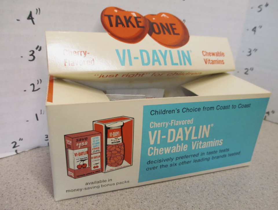 Box of Vi-Daylin cherry-flavored chewable vitamins for children, with "Take One" sign on top. The box highlights availability in money-saving bonus packs