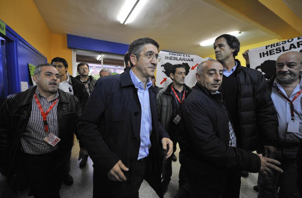 Basque Regional President or "Lehendakari", Patxi Lopez, center, leaves after voting, in Bilbao, northern Spain, Sunday Oct. 21, 2012, as pro-independence demonstrators display flags calling to return all prisoners of the Basque armed group ETA to the Basque Country. Almost 4.5 million people will go to the polls Sunday in regional elections in Spain's turbulent Basque region and in northwestern Galicia. (AP Photo/Alvaro Barrientos)