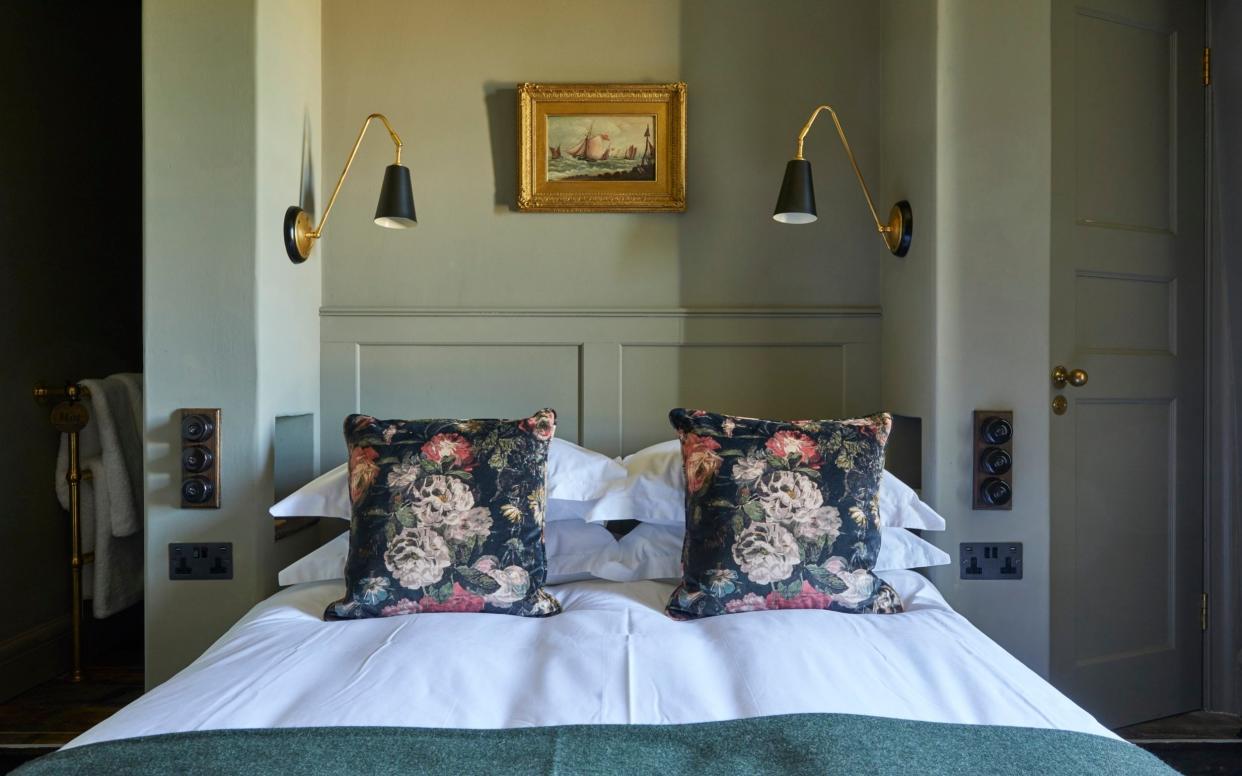 bedroom with green walls and floral pillows on bed - Jake Eastham