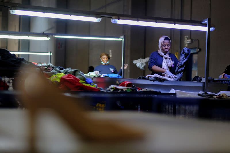 La trabajadora Cynthia, ghanesa de 44 años, participante en un programa de la fundación "Formació i Treball" ("Formación y Trabajo"), cuyo objetivo es promover la contratación de personas desempleadas especialmente vulnerables, como los inmigrantes, separa y clasifica ropa usada para empaquetar en un almacén de Sant Esteve Sesrovires, a las afueras de Barcelona, Cataluña, España