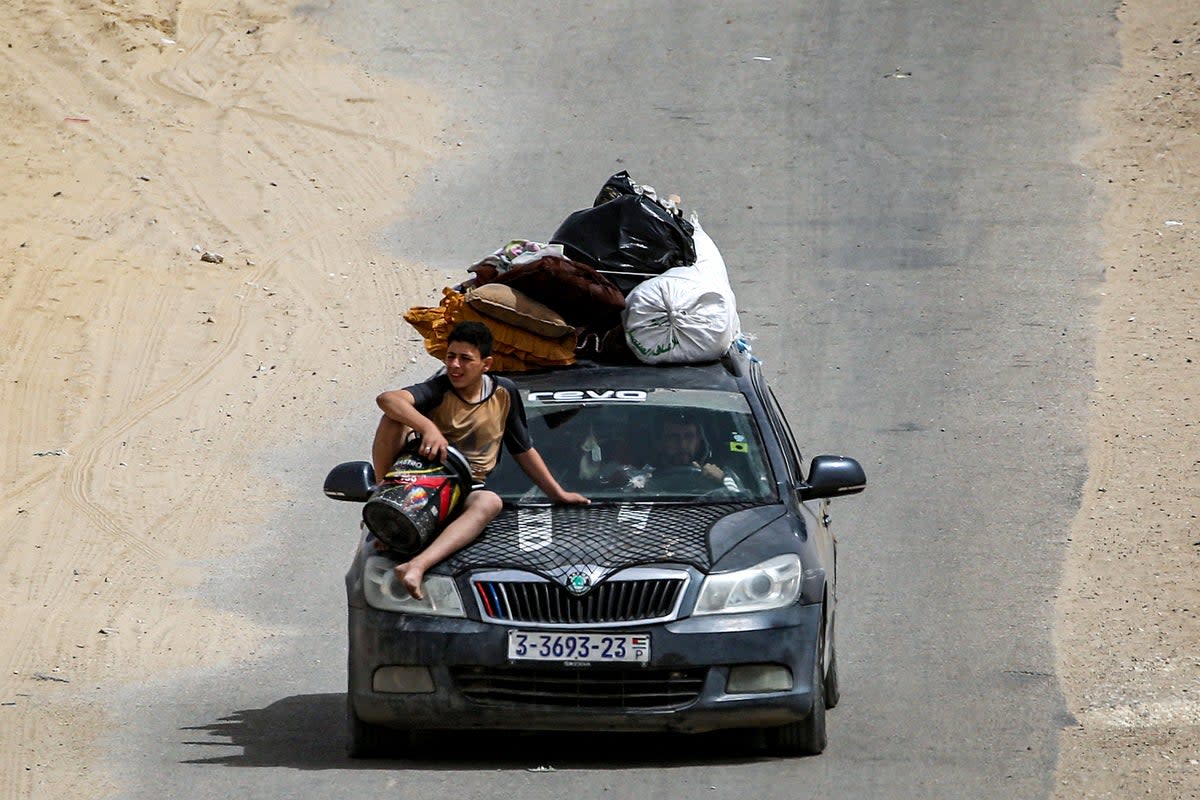 A boy sits on the hood of a vehicle loaded with belongings as members of a Palestinian family flee bound for Khan Yunis (AFP)