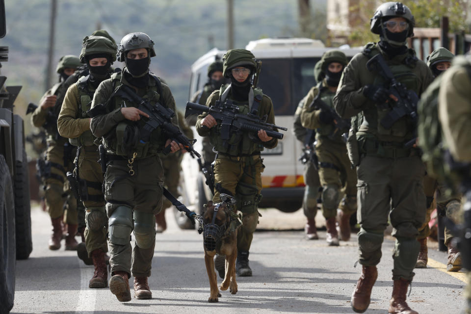 Israeli forces search for a Palestinian gunman in the village of Bruqin near the West Bank town of Salfit, Sunday, March 17, 2019. The Israeli military says a Palestinian killed an Israeli and seriously wounded two others in a West Bank shooting and stabbing spree before fleeing and setting off a massive manhunt. (AP Photo/Majdi Mohammed)