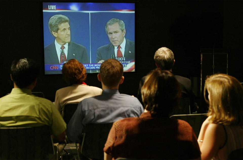 FILE - In this Oct. 14, 2004 file photo American expatriates and US Embassy staff in Manila watch as Democratic presidential candidate Sen. John Kerry, D-Mass., left, and President George W. Bush square off in the third and final televised debate. (AP Photo/Bullit Marquez, File)