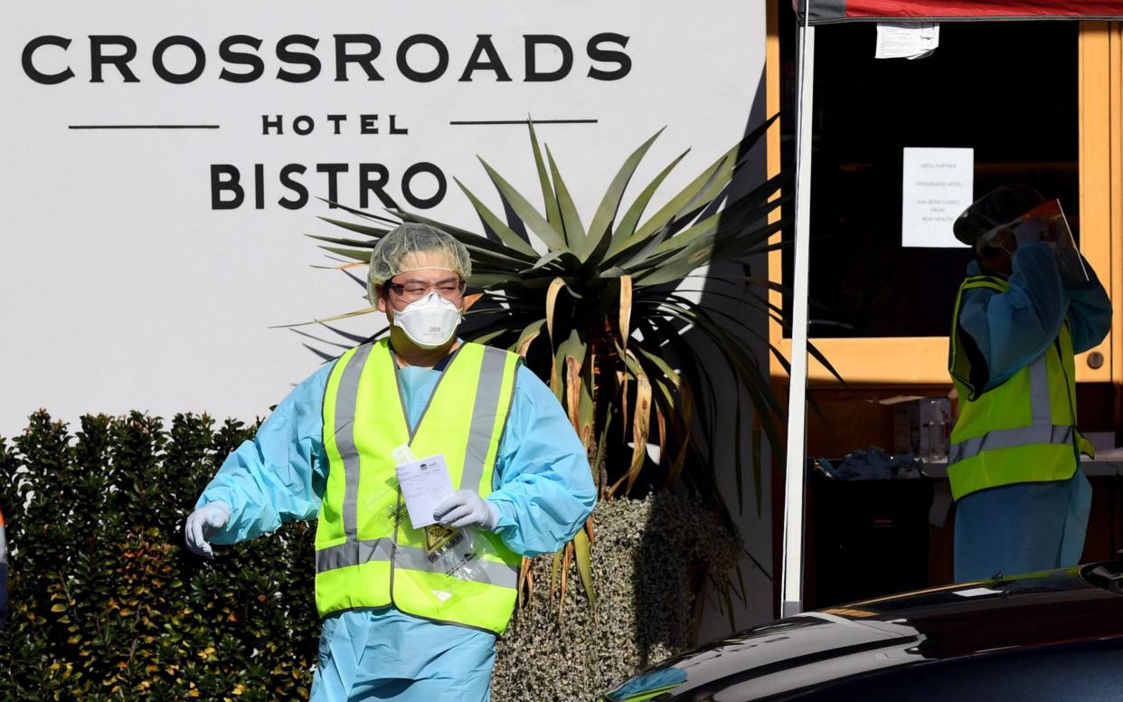 Health workers prepare to give Covid-19 tests to people in their cars at the Crossroads hotel testing centre in Sydney - Shutterstock