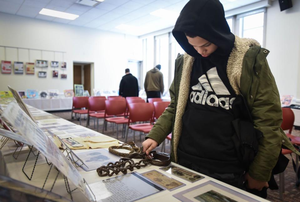 Fifth-grader Hassan Trowell of East Lansing examines some of the historical artifacts and ephemera from the Black History 101 Mobile Museum's collection, Monday, Jan. 30 2023, on display at the East Lansing Public Library.  [Matthew Dae Smith/Lansing State Journal]