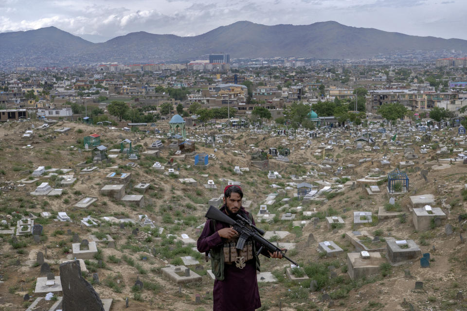 A Taliban fighter poses for a photo at a cemetery in Kabul, Afghanistan, Wednesday, May 4, 2022. There are cemeteries all over Afghanistan's capital, Kabul, many of them filled with the dead from the country's decades of war. They are incorporated casually into Afghans' lives. They provide open spaces where children play football or cricket or fly kites, where adults hang out, smoking, talking and joking, since there are few public parks. (AP Photo/Ebrahim Noroozi)